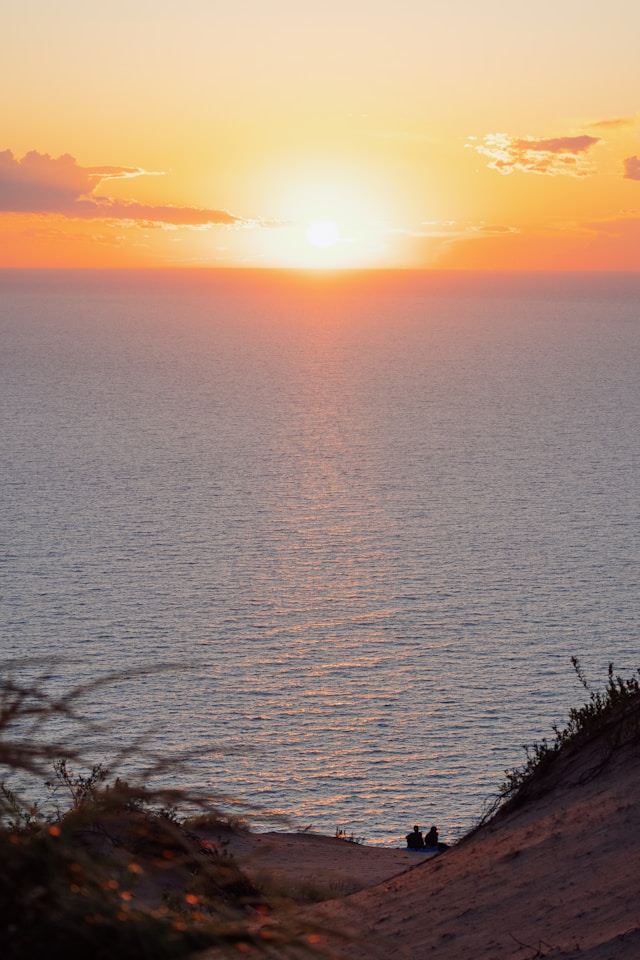 Picture of Sleeping Bear Dunes at sunset with two people watching the water